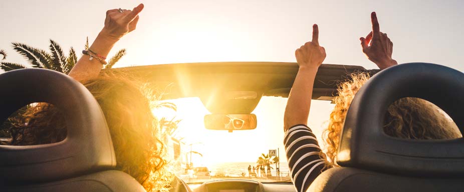 Menschen im Cabrio bei Sonnenuntergang