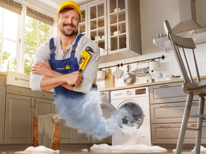 Handwerker mit Rohrzange erscheint aus auslaufender Wachmaschine 